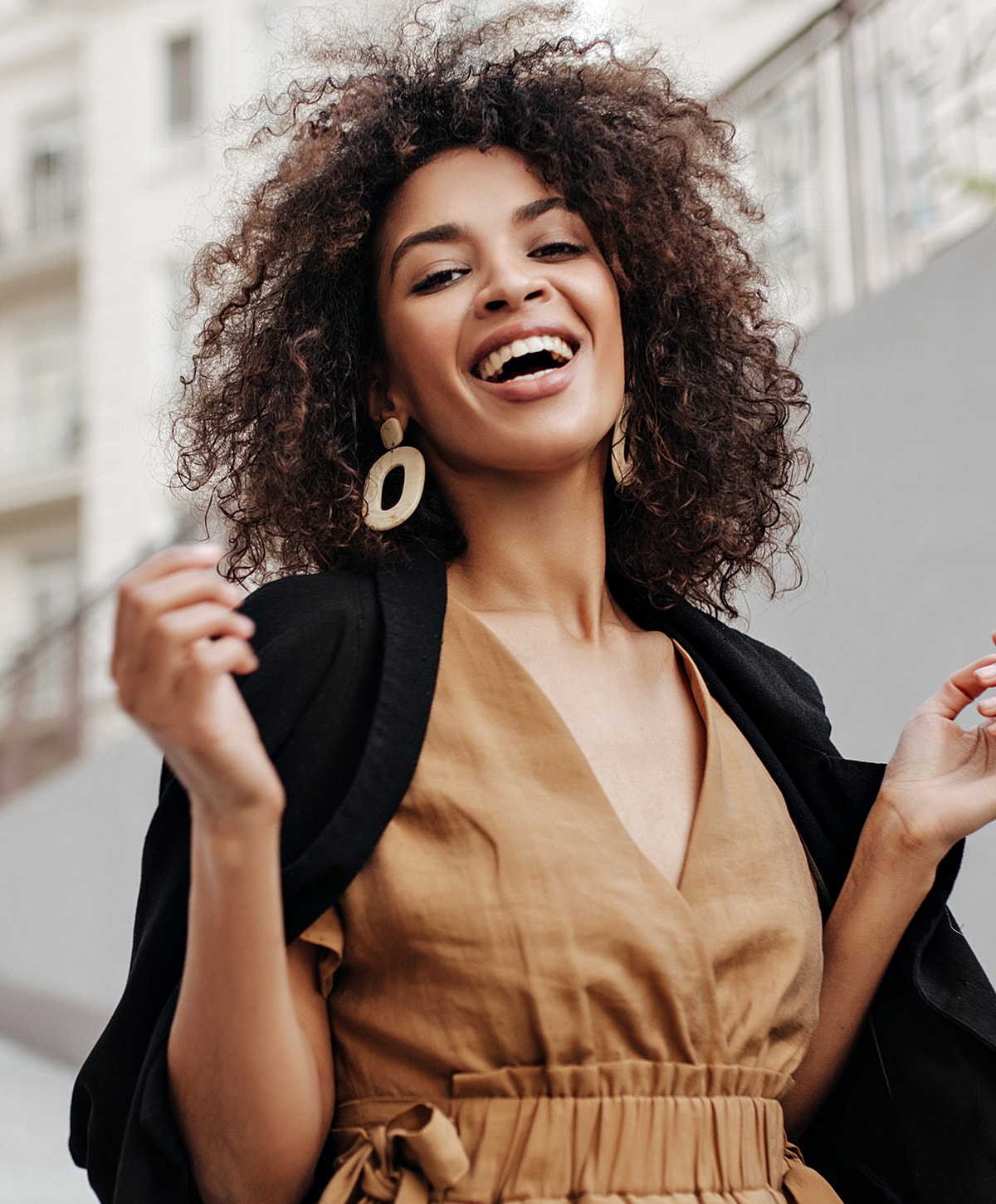 Smiling woman with curly hair in casual outfit.
