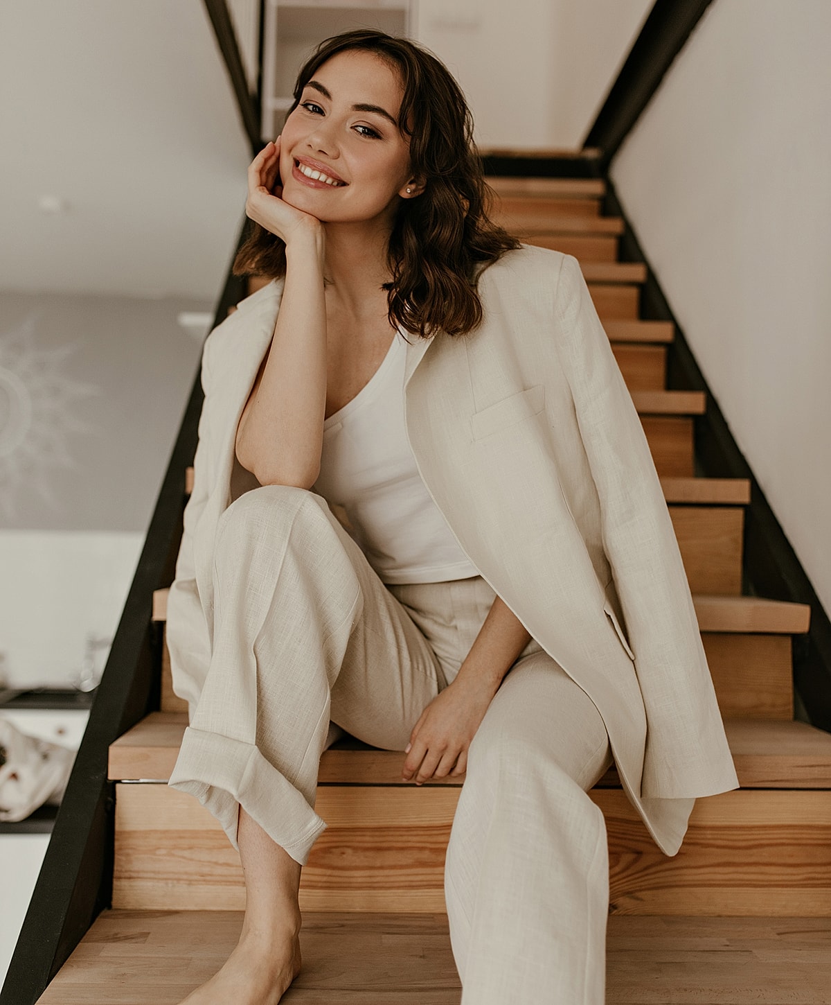 Smiling woman in stylish beige outfit on stairs.