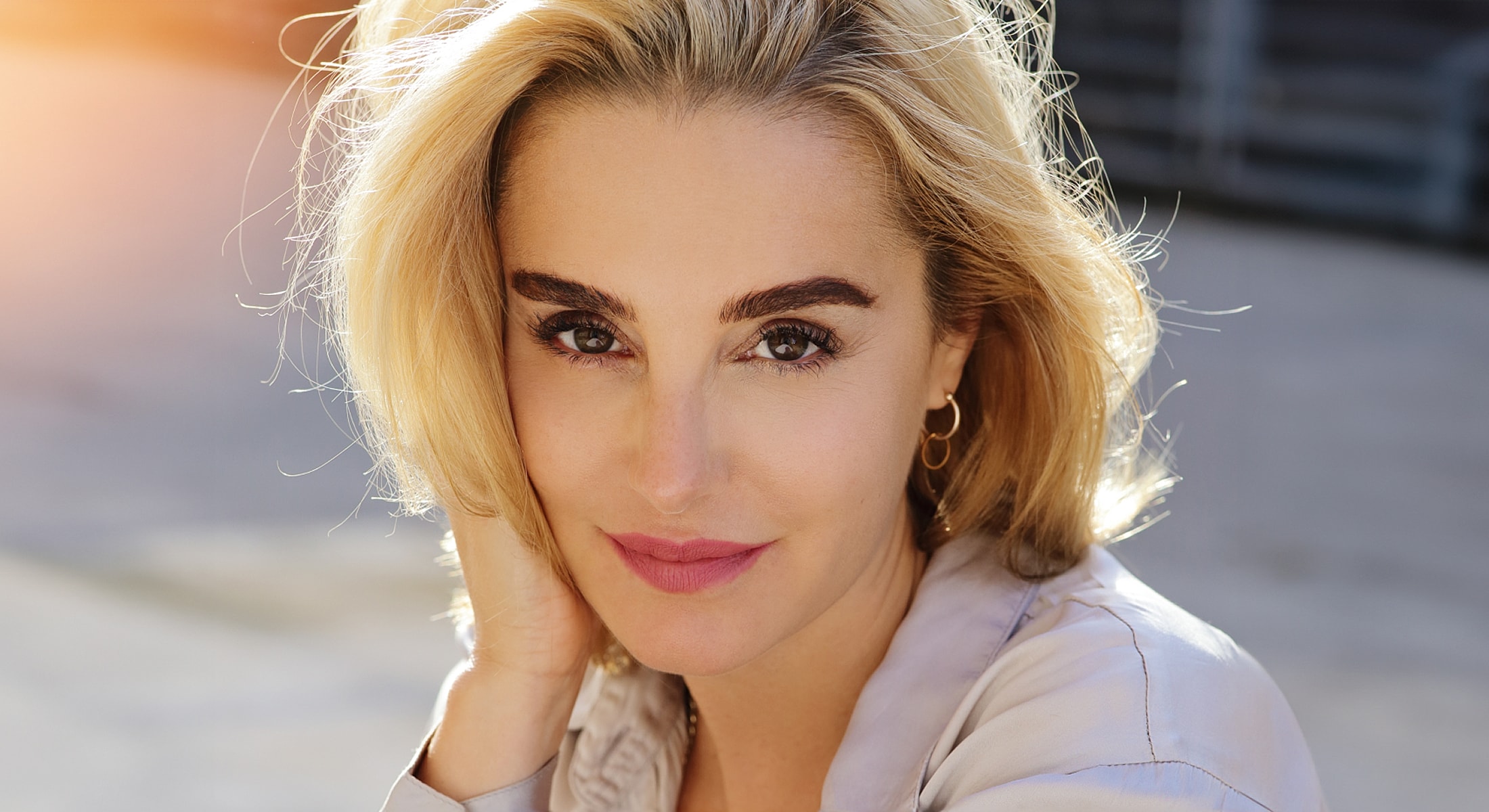 Smiling person with blonde hair and natural makeup.